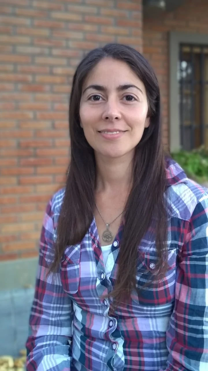Victoria Navicelli, sonriendo, frente a una pared de ladrillo